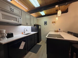A compact kitchen with a microwave, toaster, sink, and a small dining area with a table and chairs. - Walk to Giant Steps •1BR+Loft • Fireplace• Fast Wi-Fi• Sleeps 6 •Mountain Views (Brian Head)