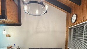 A cozy living area with a sectional sofa, a wooden table, and a chandelier. - Walk to Giant Steps •1BR+Loft • Fireplace• Fast Wi-Fi• Sleeps 6 •Mountain Views (Brian Head)