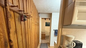 A narrow hallway with wooden walls, a kitchen area with a coffee maker and toaster, and a small window. - Walk to Giant Steps •1BR+Loft • Fireplace• Fast Wi-Fi• Sleeps 6 •Mountain Views (Brian Head)