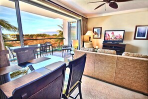Ein modernes Hotelzimmer mit Balkon, Essbereich, Sofa und Fernseher.