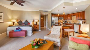 Ein Hotelzimmer mit Bett, Schreibtisch, Stuhl, Couchtisch, einer Küchenzeile und einem Deckenventilator.