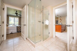 A hotel room with a glass-enclosed shower, a bed with a patterned bedspread, and a view of the outside. - Honua Kai | Ocean View 6 BR, Sleeps 22 | Car Incl. w/ 6+ Nights | HKH ML-1748 by KBM (Lahaina)