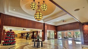 Un vestíbulo de hotel con una recepción, un árbol de Navidad y una zona de estar circular.
