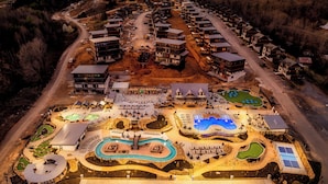 An aerial view of a resort with multiple buildings, a swimming pool, and a golf course. - Star Gazer Luxury Rooftop Cabin (Sevierville)