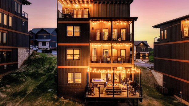 A multi-story building with balconies, string lights, and a visible outdoor seating area. - Star Gazer Luxury Rooftop Cabin (Sevierville)