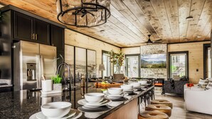 A modern kitchen with a long island, black cabinets, stainless steel appliances, and a stone accent wall. - Star Gazer Luxury Rooftop Cabin (Sevierville)