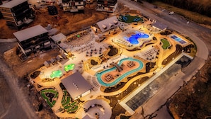 An aerial view of a resort with multiple swimming pools, a large covered area, and a variety of outdoor seating arrangements. - Star Gazer Luxury Rooftop Cabin (Sevierville)