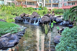 A hotel with a landscaped garden featuring a small waterfall, rocks, and lush greenery.