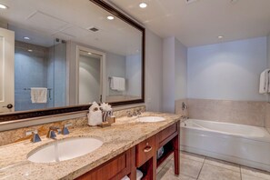 Une salle de bain avec deux lavabos, un grand miroir, une baignoire et un espace douche.