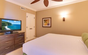 Ein Hotelzimmer mit Bett, Fernseher auf einer Holzkommode, einer Tür und einem gerahmten Bild an der Wand.