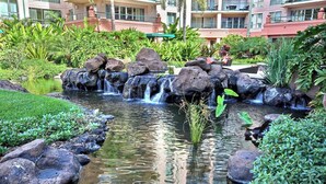 A landscaped garden with a small waterfall, rocks, and lush greenery. - Honua Kai | Ocean View 4 BR, Sleeps 14 | Car Incl. w/ 6+ Nights | HKH ML-1769 by KBM (Lahaina)
