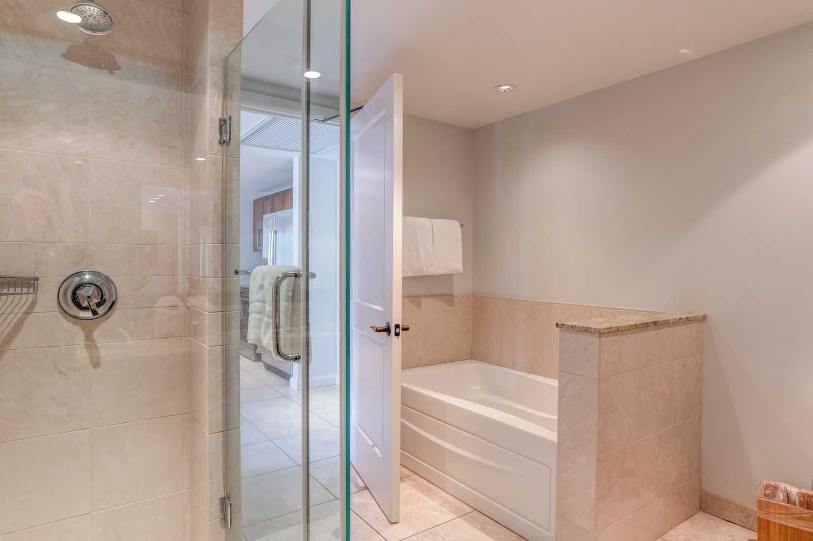 Un baño moderno con ducha de mampara de vidrio, bañera y puerta de cristal.