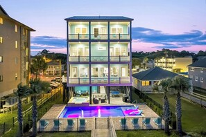 Un immeuble à plusieurs étages doté d’un espace piscine, comprenant un jacuzzi et des chaises longues.