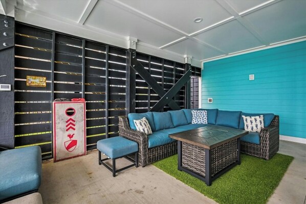 Un espace extérieur aménagé avec un coin salon abrité, comprenant un canapé bleu, une petite table et un banc.