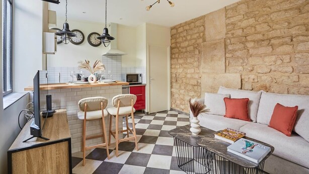 A compact living space with a kitchen area, a dining table with chairs, a sofa with cushions, and a decorative vase. - Sublim Apartement Center of Paris (Paris)