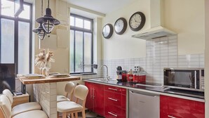 A kitchen with red cabinets, a microwave, a sink, and a window with a view. - Sublim Apartement Center of Paris (Paris)