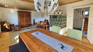 A spacious dining area with a wooden table, green chairs, and a decorative ceiling light fixture. - Charming country house with garden - lakes & foothills of the Alps (Penzberg)