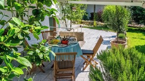 A patio with a table set for dining, surrounded by potted plants and a pergola. - Charming country house with garden - lakes & foothills of the Alps (Penzberg)