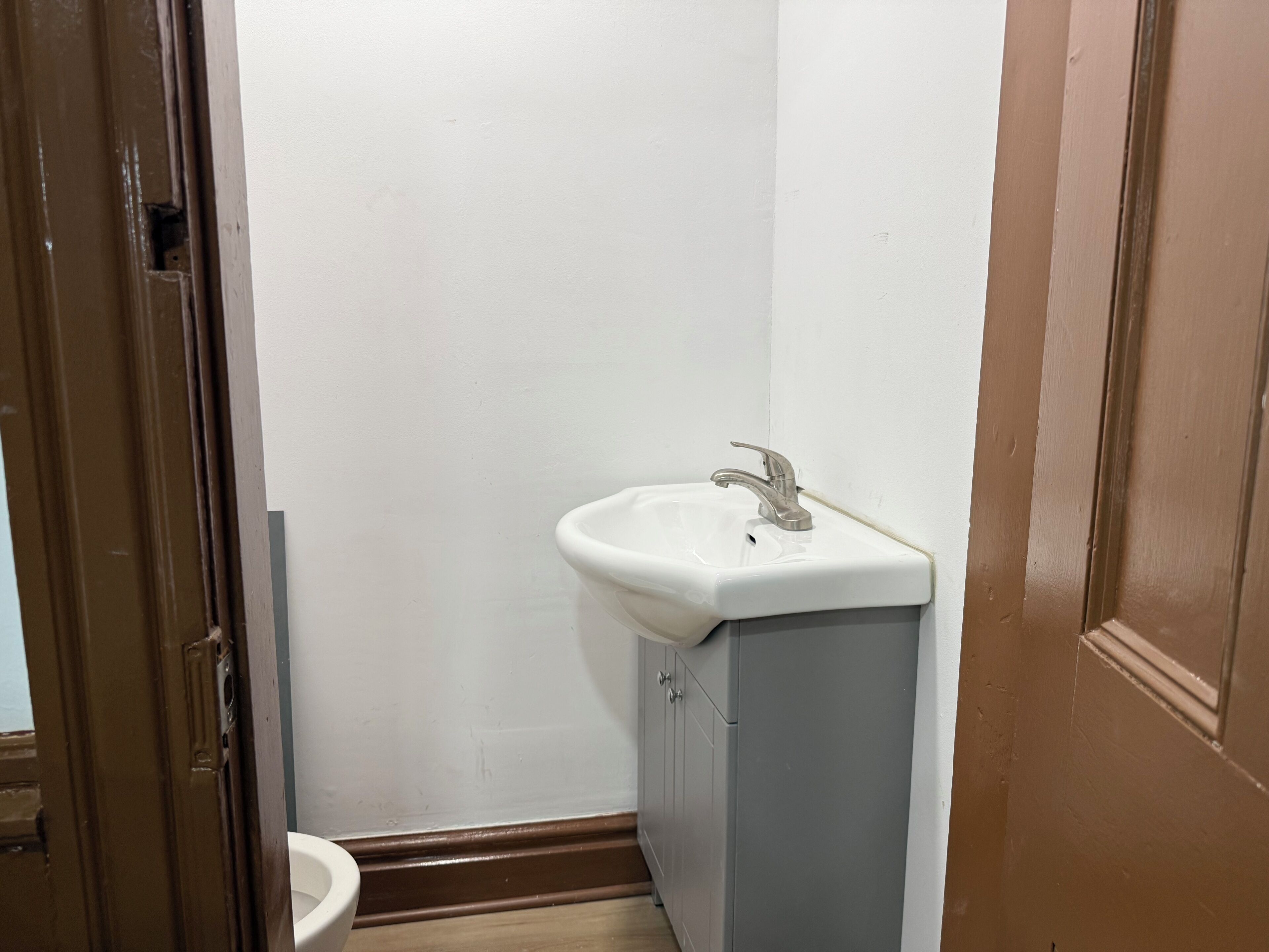 A bathroom with a white sink, a toilet, and a door.