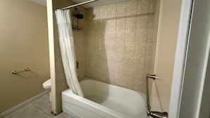 A bathroom with a bathtub, a shower area, and a toilet.