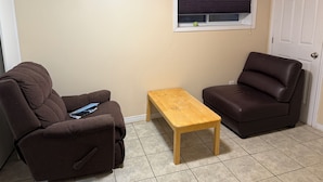 A room with two brown sofas, a wooden table, a window with blinds, and a white door.
