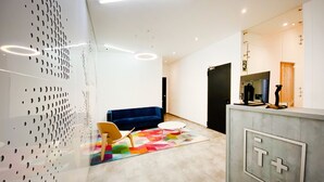 Un interior moderno con un sofá azul, una silla de madera y una alfombra colorida.