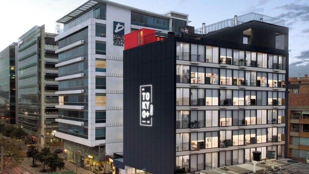 Un edificio moderno de varios pisos con un llamativo letrero 'TOKYO O+1' en la fachada.