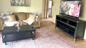 Un salon avec un canapé, une table basse, un téléviseur et des œuvres d’art.