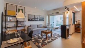 A modern living room with a sofa, dining table, and kitchen area.