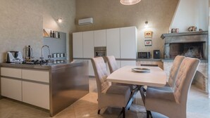 A modern kitchen with a central island, white cabinetry, and a dining area with a table and chairs.