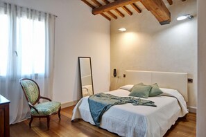 A bedroom with a bed, a chair, a mirror, and a wooden ceiling.