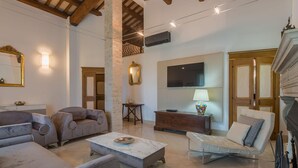 A spacious living room with a high ceiling, a fireplace, and a television.