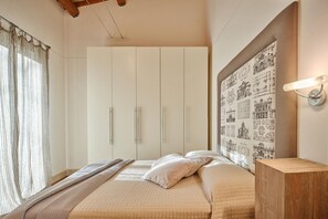 A bedroom with a bed, a wardrobe, a headboard with a cityscape print, and a bedside table.