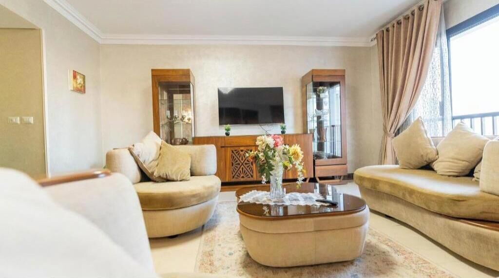 A living room with a sofa set, a coffee table, and a TV mounted on the wall.