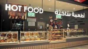 A food counter with various dishes displayed in glass cases, labeled "HOT FOOD" and "Arabic Cuisine".