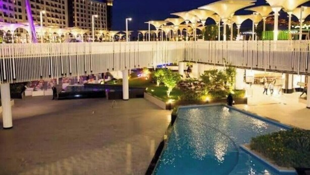 A hotel with a swimming pool, outdoor seating areas, and a covered walkway.