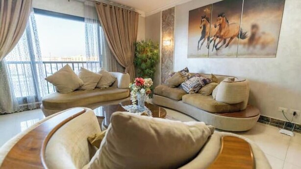 A modern living room with two sofas, a coffee table, and a large window with curtains. - Duplex w/ Pool View Near AUC (New Cairo City)