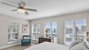 A bedroom with a bed, a desk, a chair, and a ceiling fan.