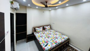 A bedroom with a bed, a ceiling fan, recessed lighting, and a wardrobe. - Kashi Nagri Varanasi - Kashi Residency (Varanasi)