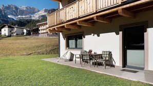 A building with a balcony, outdoor seating, and a view of mountains. - Apartment 'Cesa Pattis' with Mountain View, Private Garden and Wi-Fi (Mazzin)