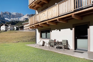 A building with a balcony, outdoor seating, and a view of mountains.