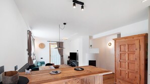 A modern kitchen with a wooden island, a dining area with a sofa, and a large wooden wardrobe. - Apartment 'Cesa Pattis' with Mountain View, Private Garden and Wi-Fi (Mazzin)