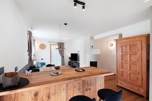 A modern kitchen with a wooden island, a dining area with a sofa, and a large wooden wardrobe.