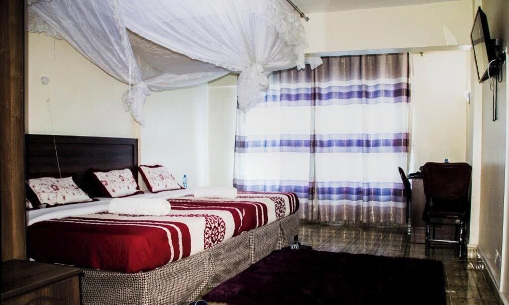 A bedroom with a bed, a chair, a mosquito net, and a striped curtain.
