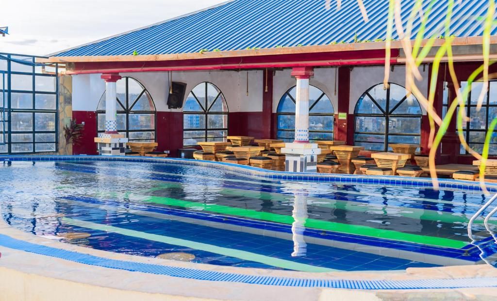 Piscina com espreguiçadeiras e área de estar coberta com janelas em arco.