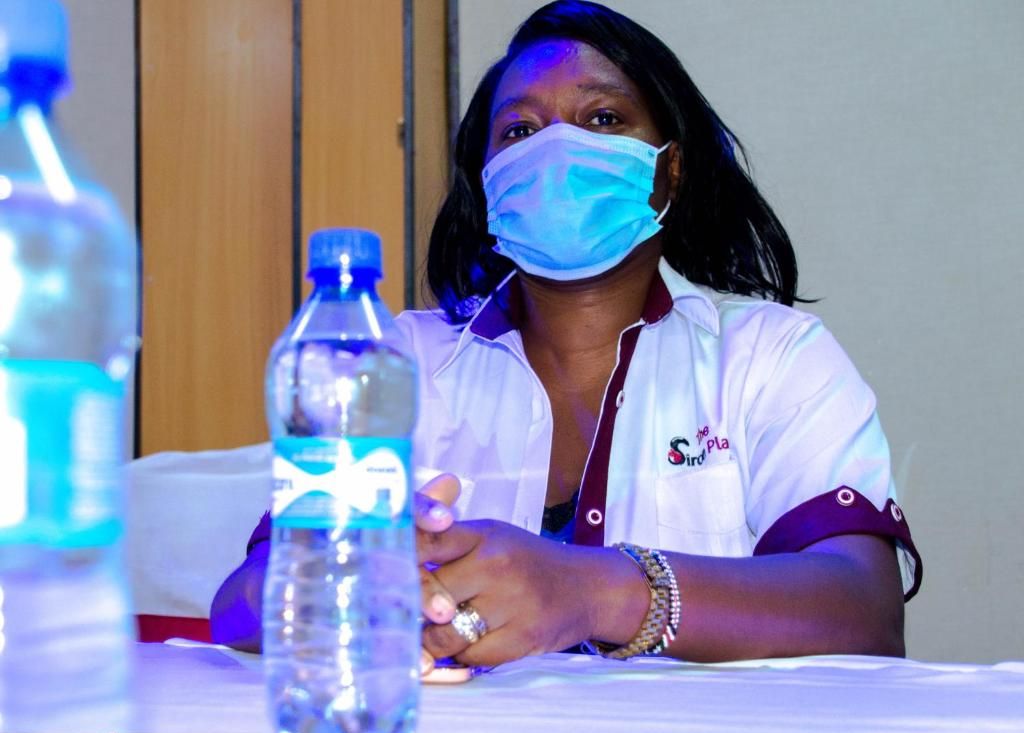 A person seated at a table with a water bottle in front of them.
