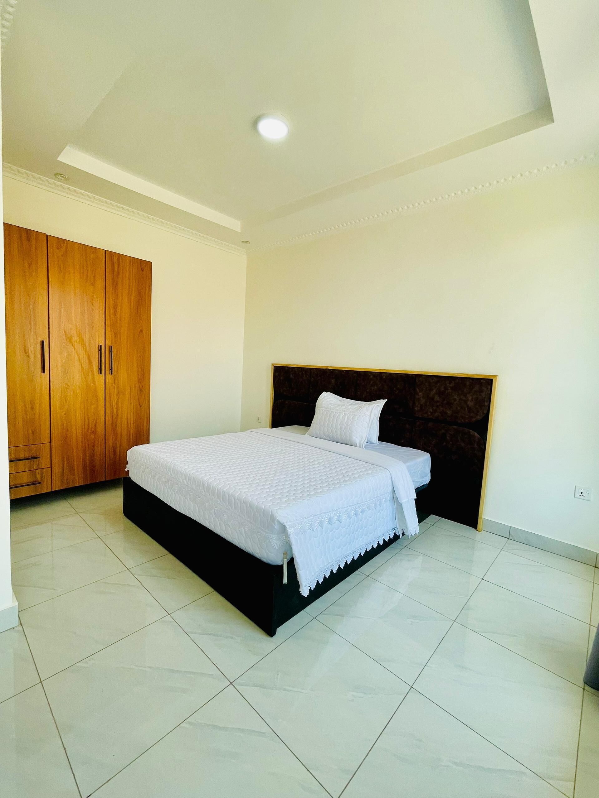 A bedroom with a bed, a wardrobe, and a ceiling light.