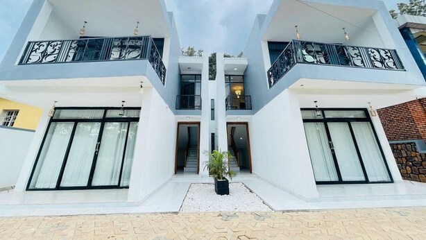 Een modern huis met twee verdiepingen, met een symmetrisch ontwerp, grote ramen, balkons en een centrale trap.