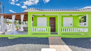 A bright green building with a tiled roof, white shutters, and a small porch with a white balustrade. - Sunset Marena/Beach Front House (Stella)