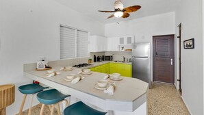 A modern kitchen with a central island, white cabinets, a microwave, and a refrigerator. - Sunset Marena/Beach Front House (Stella)
